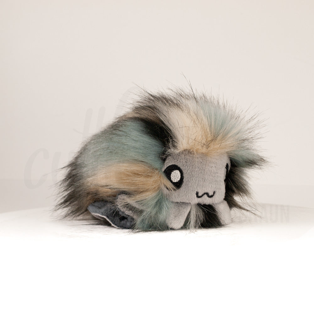 Front view of a cuttlepod plush toy, captured at a slight angle to highlight its charming features: large, cartoonish eyes, ruffled fins, and a cuddly, furry texture.