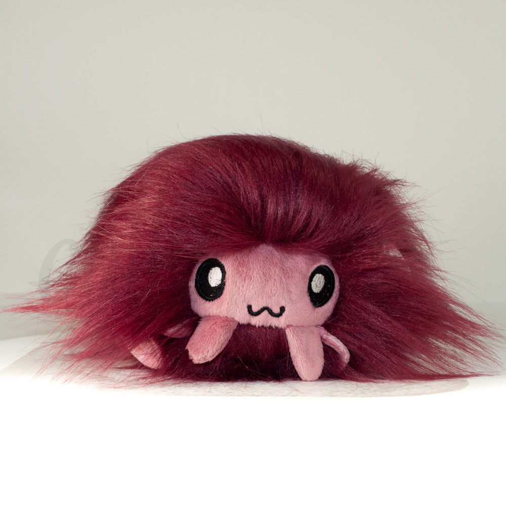 Front view of a cuttlepod plush toy, showcasing its unique form with large, cartoonish eyes, ruffled fins, and a cuddly, furry texture.