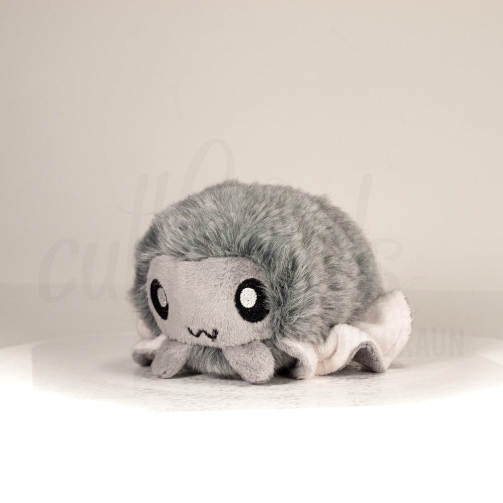 Front view of a cuttlepod plush toy, captured at a slight angle to highlight its charming features: large, cartoonish eyes, ruffled fins, and a cuddly, furry texture.