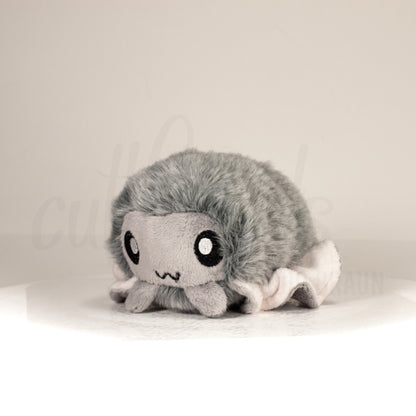 Front view of a cuttlepod plush toy, captured at a slight angle to highlight its charming features: large, cartoonish eyes, ruffled fins, and a cuddly, furry texture.