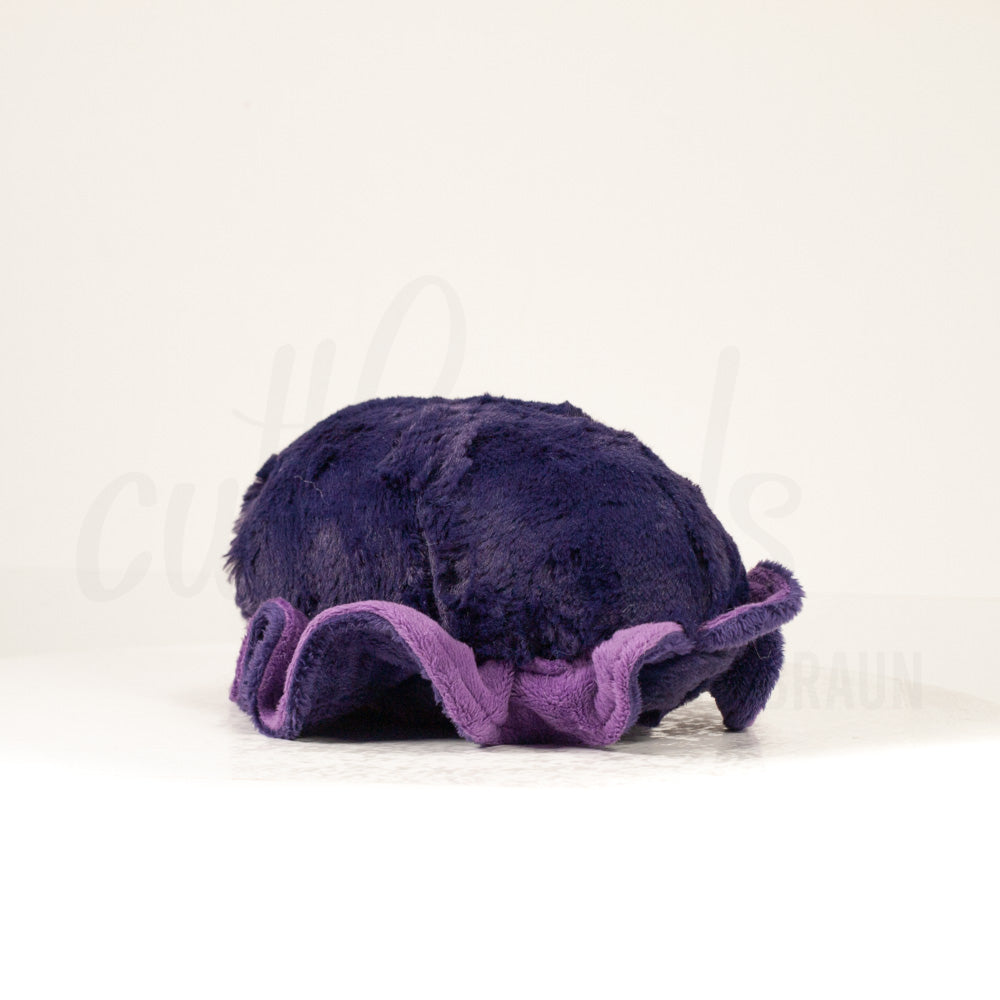 Slightly angled back view of a cuttlepod plush toy, highlighting two-tone ruffled fins, and a cuddly, furry body that comes to a soft point at the rear.