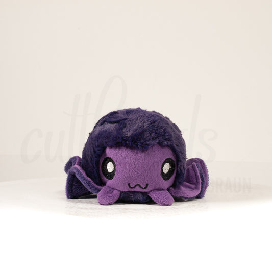 Front view of a cuttlepod plush toy, showcasing its unique form with large, cartoonish eyes, ruffled fins, and a cuddly, furry texture.