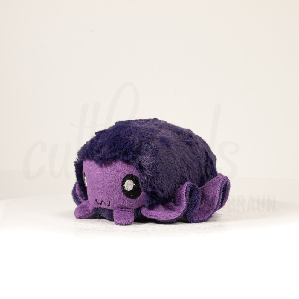 Front view of a cuttlepod plush toy, captured at a slight angle to highlight its charming features: large, cartoonish eyes, ruffled fins, and a cuddly, furry texture.