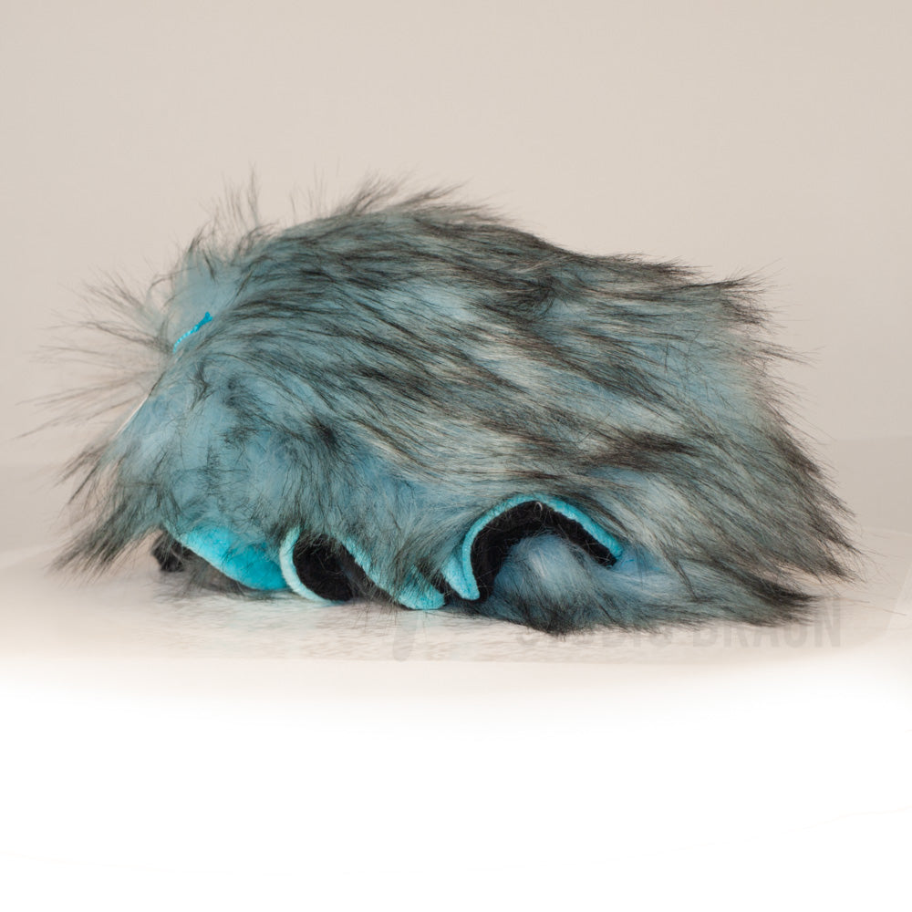 Slightly angled back view of a cuttlepod plush toy, highlighting two-tone ruffled fins, and a cuddly, furry body that comes to a soft point at the rear.