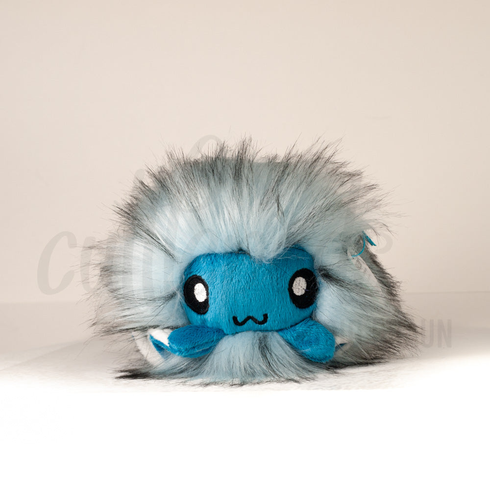 Front view of a cuttlepod plush toy, showcasing its unique form with large, cartoonish eyes, ruffled fins, and a cuddly, furry texture.