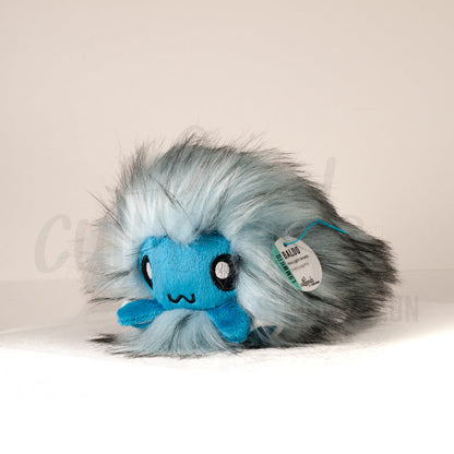 Front view of a cuttlepod plush toy, captured at a slight angle to highlight its charming features: large, cartoonish eyes, ruffled fins, and a cuddly, furry texture.