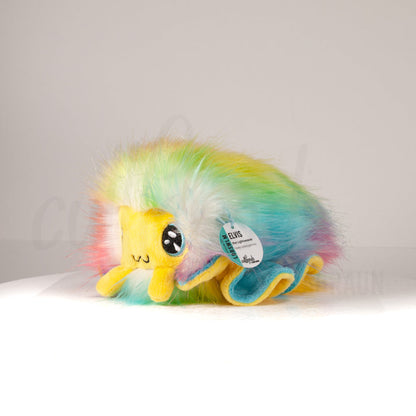 Front view of a cuttlepod plush toy, captured at a slight angle to highlight its charming features: large, cartoonish eyes, ruffled fins, and a cuddly, furry texture.