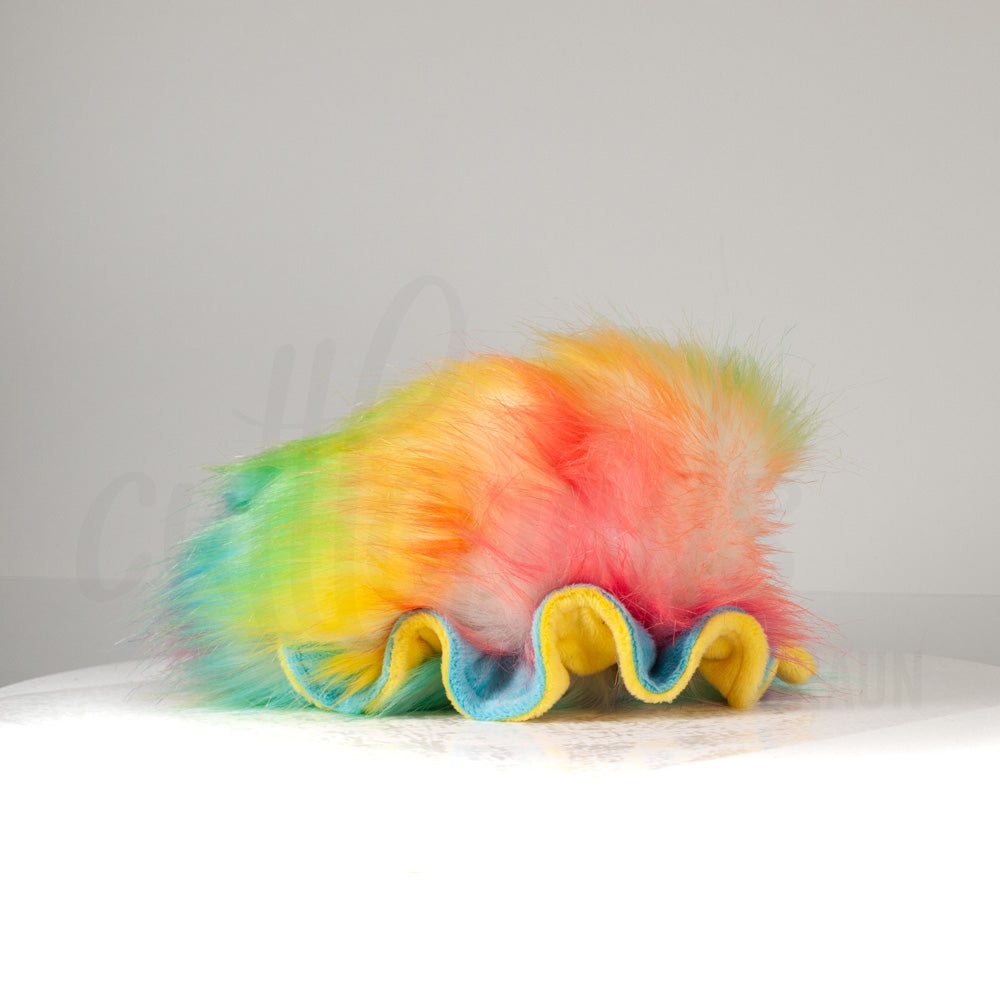 Side profile view of a cuttlepod plush toy, showcasing two-tone ruffled fins, and a cuddly, furry body.