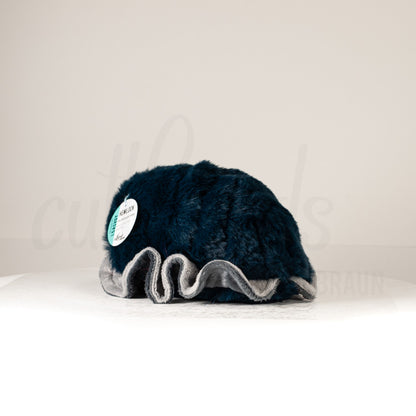 Slightly angled back view of a cuttlepod plush toy, highlighting two-tone ruffled fins, and a cuddly, furry body that comes to a soft point at the rear.