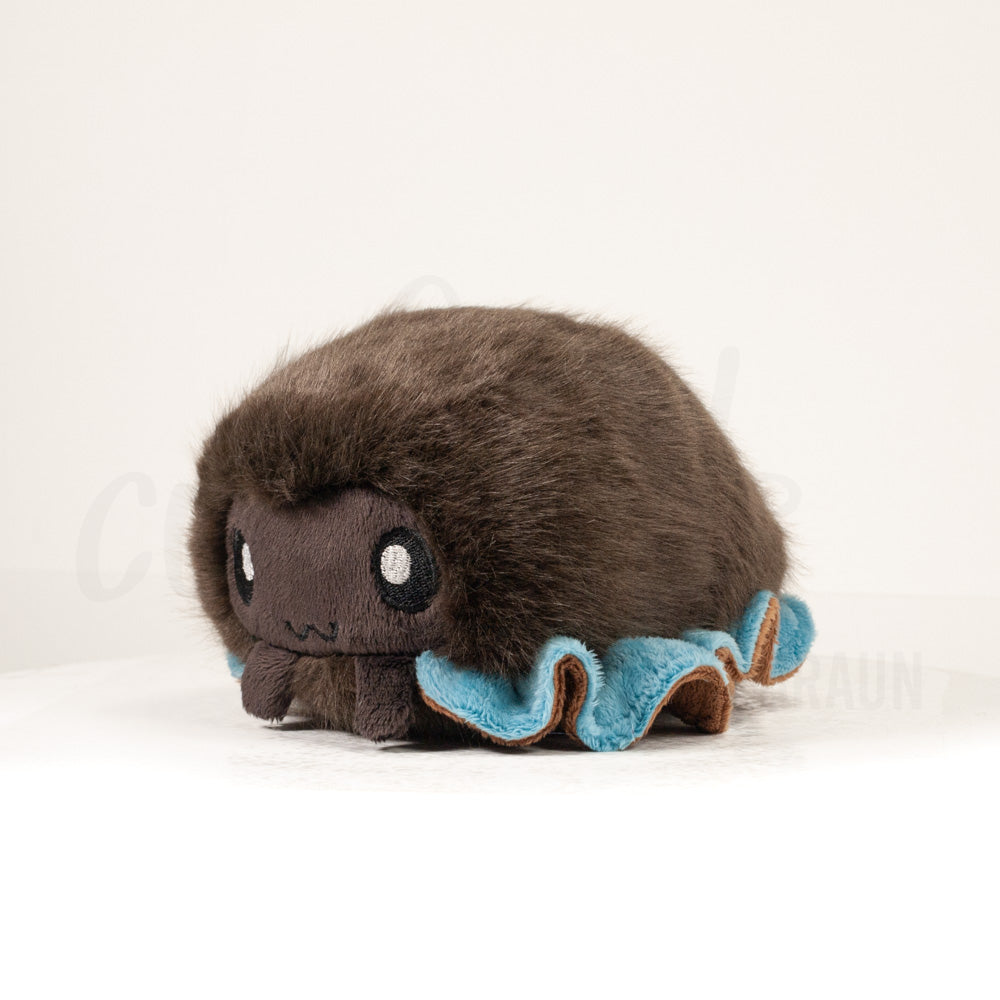 Front view of a cuttlepod plush toy, captured at a slight angle to highlight its charming features: large, cartoonish eyes, ruffled fins, and a cuddly, furry texture.