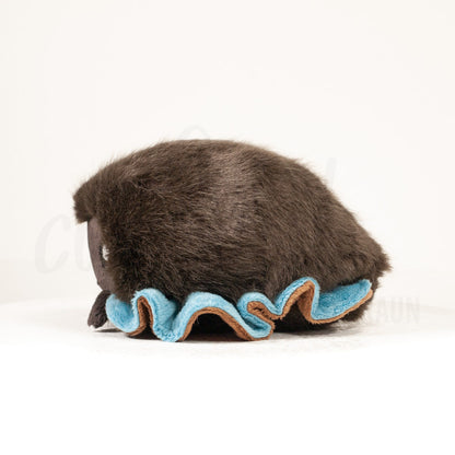 Side profile view of a cuttlepod plush toy, showcasing two-tone ruffled fins, and a cuddly, furry body.