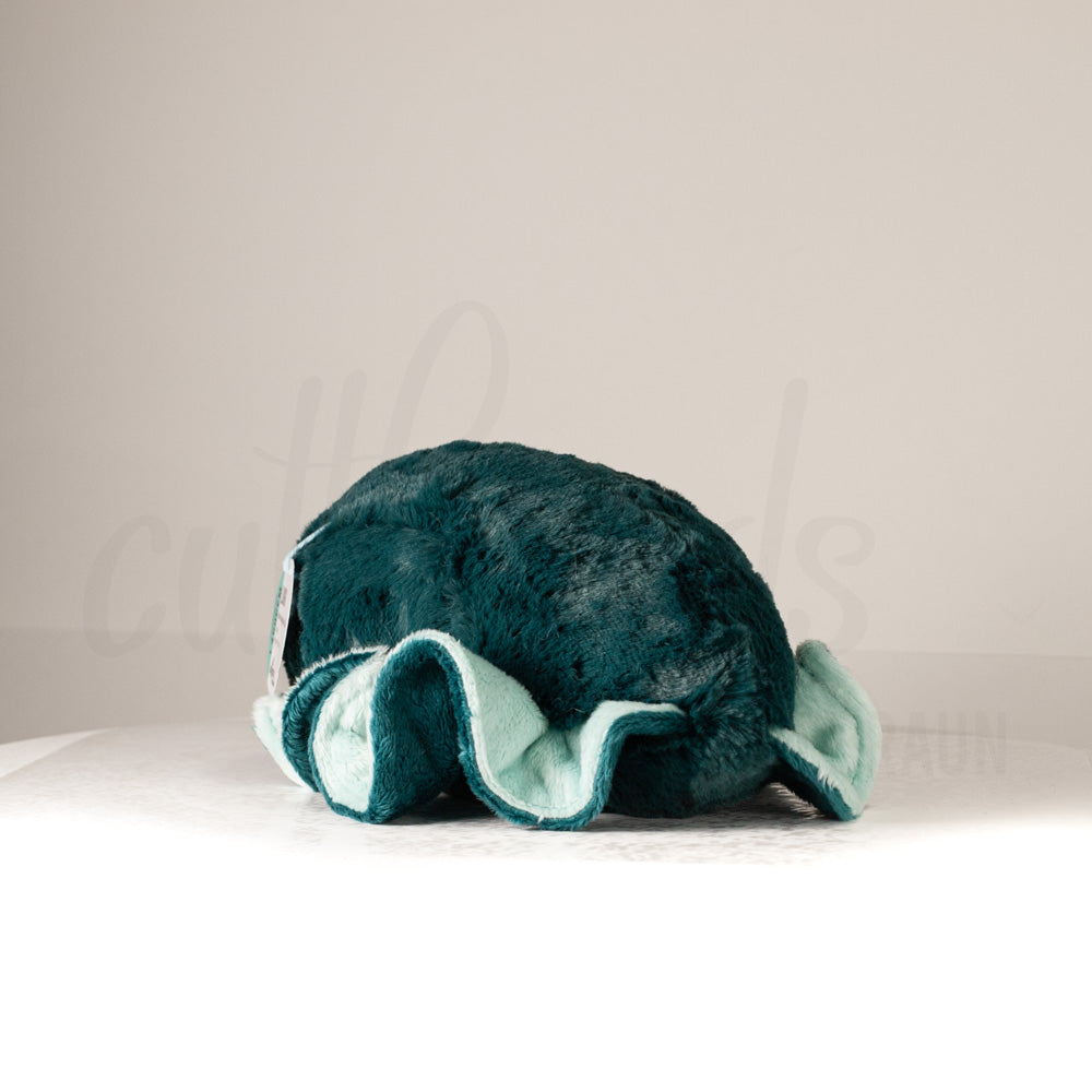 Slightly angled back view of a cuttlepod plush toy, highlighting two-tone ruffled fins, and a cuddly, furry body that comes to a soft point at the rear.