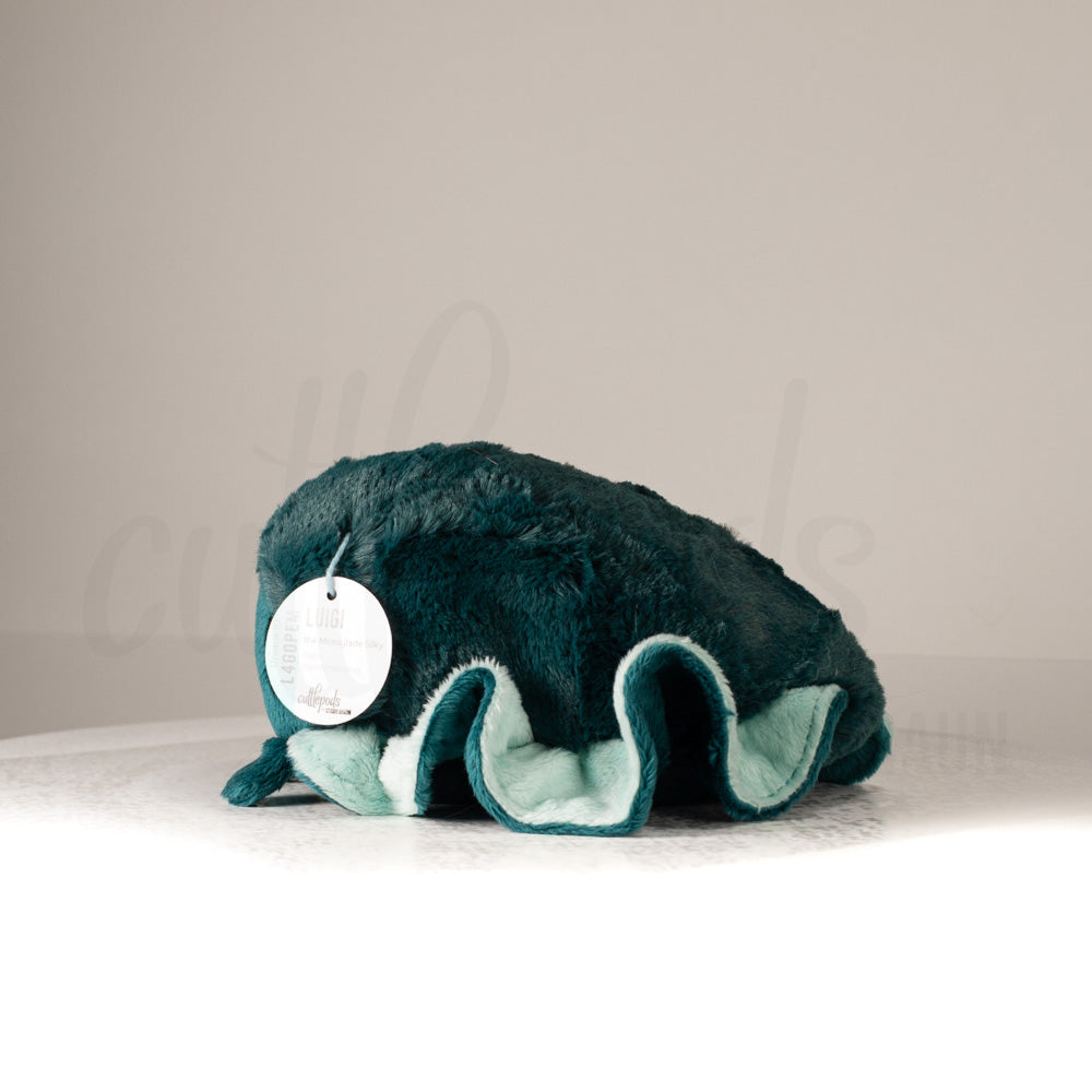 Side profile view of a cuttlepod plush toy, showcasing two-tone ruffled fins, and a cuddly, furry body.