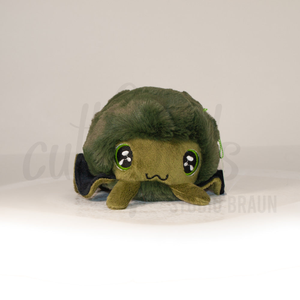 Front view of a cuttlepod plush toy, showcasing its unique form with large, cartoonish eyes, ruffled fins, and a cuddly, furry texture.