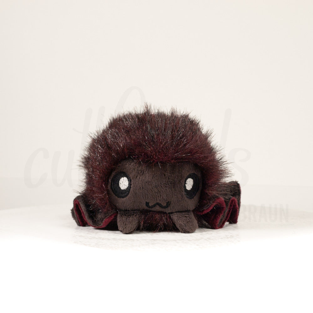 Front view of a cuttlepod plush toy, showcasing its unique form with large, cartoonish eyes, ruffled fins, and a cuddly, furry texture.