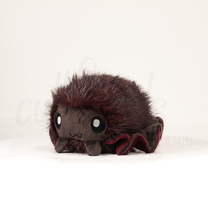 Front view of a cuttlepod plush toy, captured at a slight angle to highlight its charming features: large, cartoonish eyes, ruffled fins, and a cuddly, furry texture.