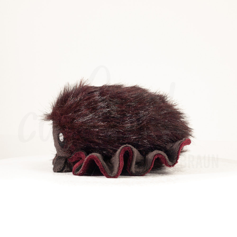 Side profile view of a cuttlepod plush toy, showcasing two-tone ruffled fins, and a cuddly, furry body.