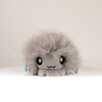 Front view of a cuttlepod plush toy, showcasing its unique form with large, cartoonish eyes, ruffled fins, and a cuddly, furry texture.