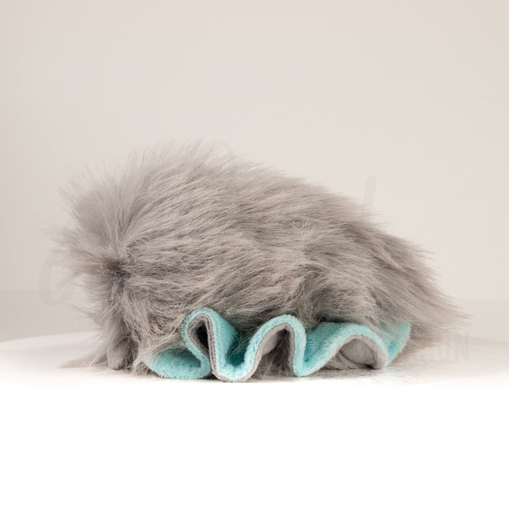 Slightly angled back view of a cuttlepod plush toy, highlighting two-tone ruffled fins, and a cuddly, furry body that comes to a soft point at the rear.