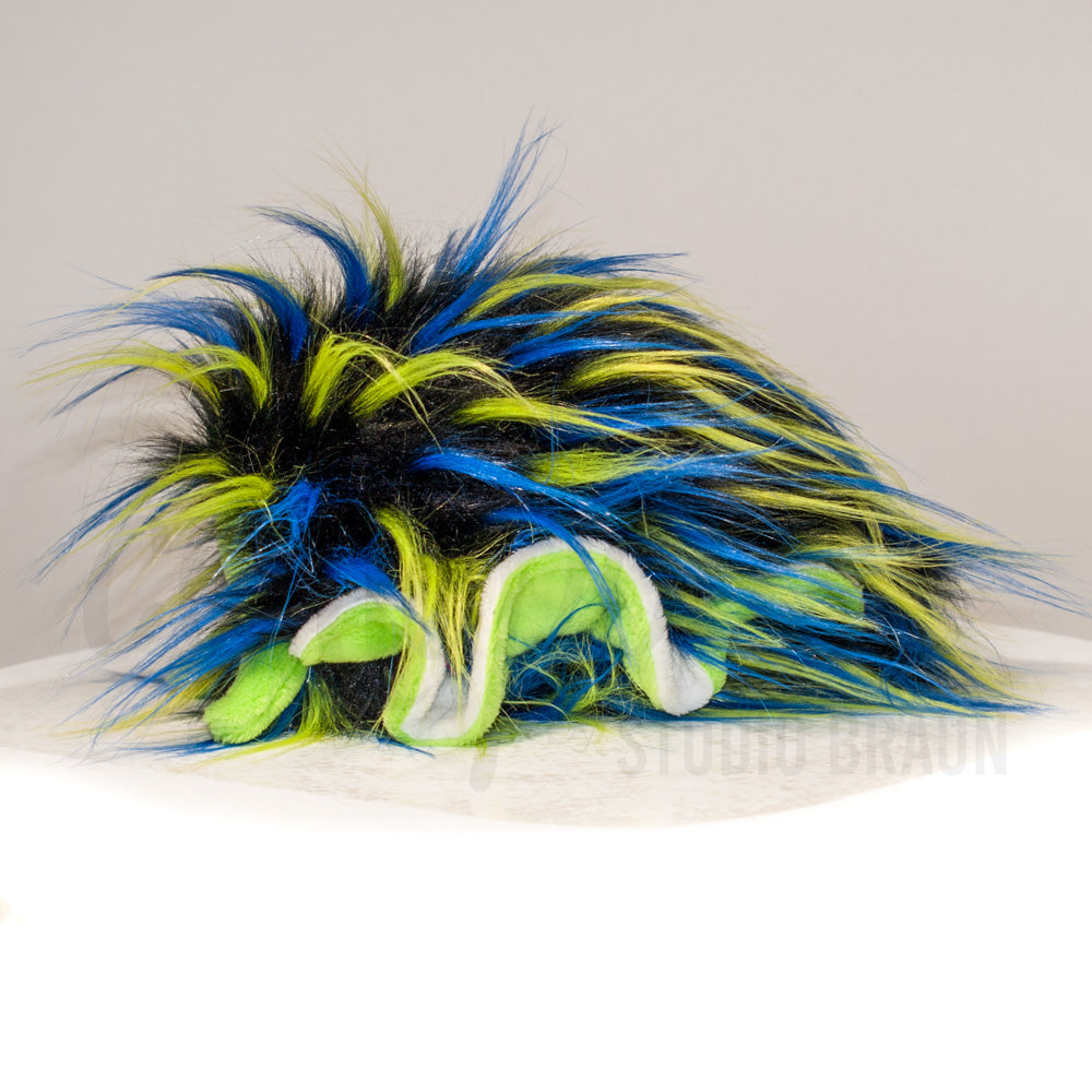 Side profile view of a cuttlepod plush toy, showcasing two-tone ruffled fins, and a cuddly, furry body.