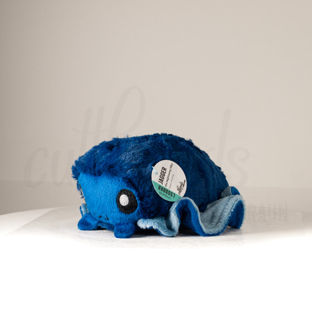 Front view of a cuttlepod plush toy, captured at a slight angle to highlight its charming features: large, cartoonish eyes, ruffled fins, and a cuddly, furry texture.