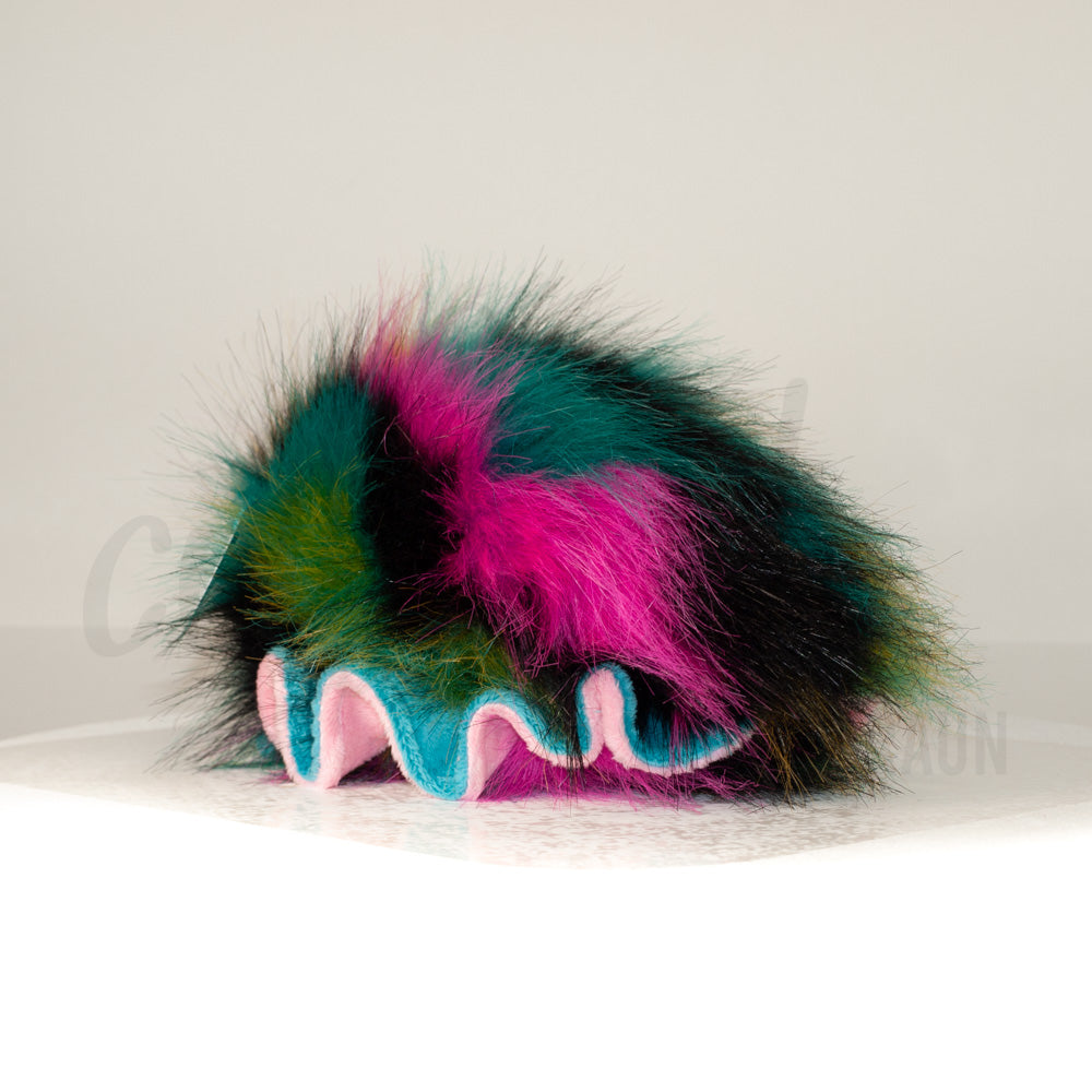 Slightly angled back view of a cuttlepod plush toy, highlighting two-tone ruffled fins, and a cuddly, furry body that comes to a soft point at the rear.