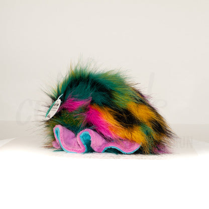 Slightly angled back view of a cuttlepod plush toy, highlighting two-tone ruffled fins, and a cuddly, furry body that comes to a soft point at the rear.