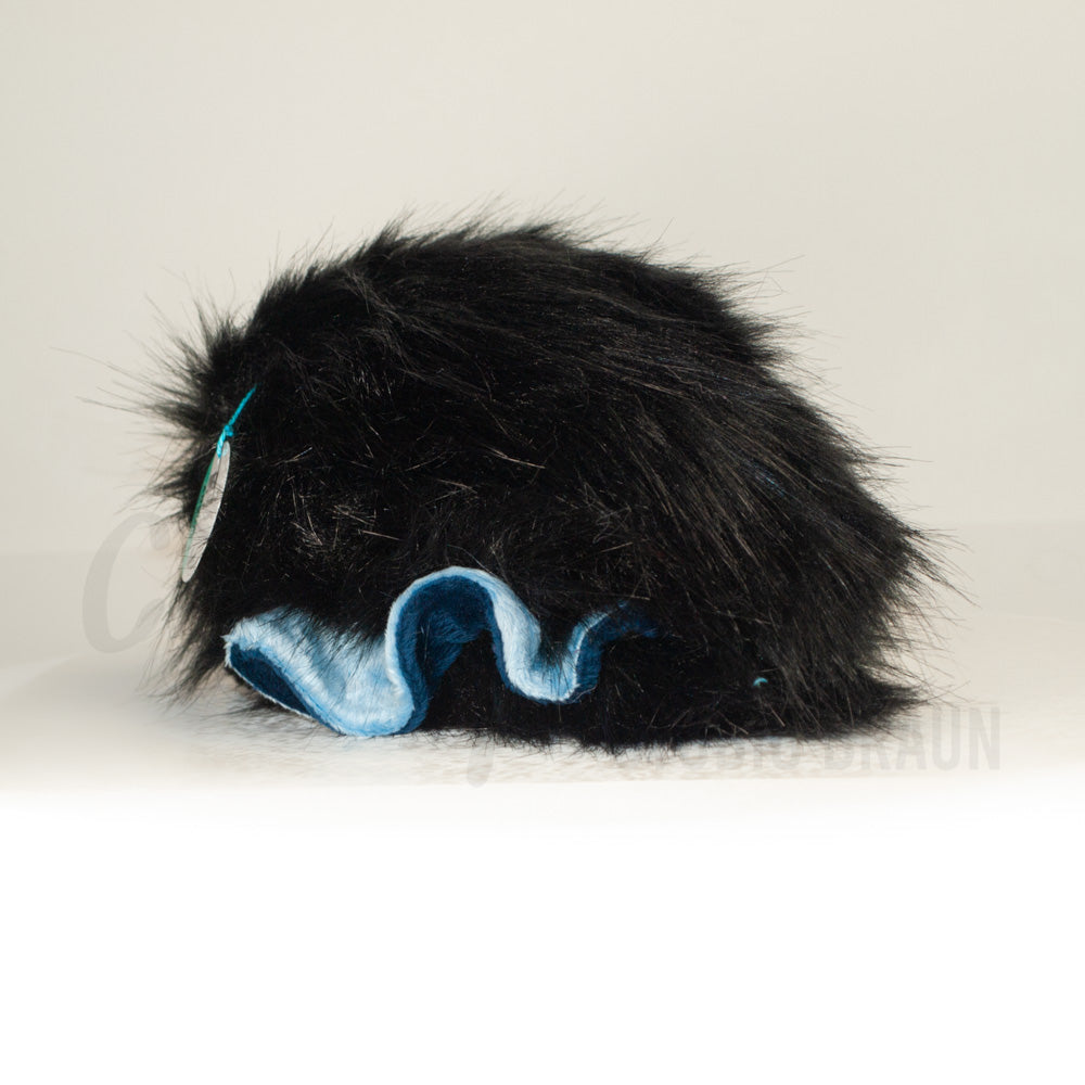 Slightly angled back view of a cuttlepod plush toy, highlighting two-tone ruffled fins, and a cuddly, furry body that comes to a soft point at the rear.