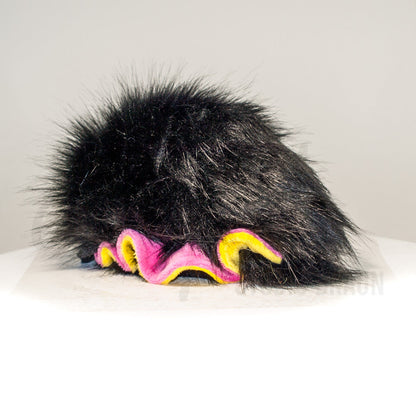 Slightly angled back view of a cuttlepod plush toy, highlighting two-tone ruffled fins, and a cuddly, furry body that comes to a soft point at the rear.