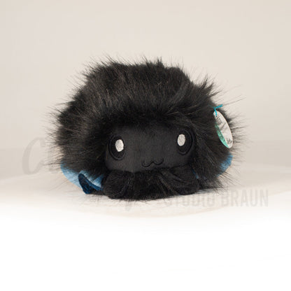 Front view of a cuttlepod plush toy, showcasing its unique form with large, cartoonish eyes, ruffled fins, and a cuddly, furry texture.