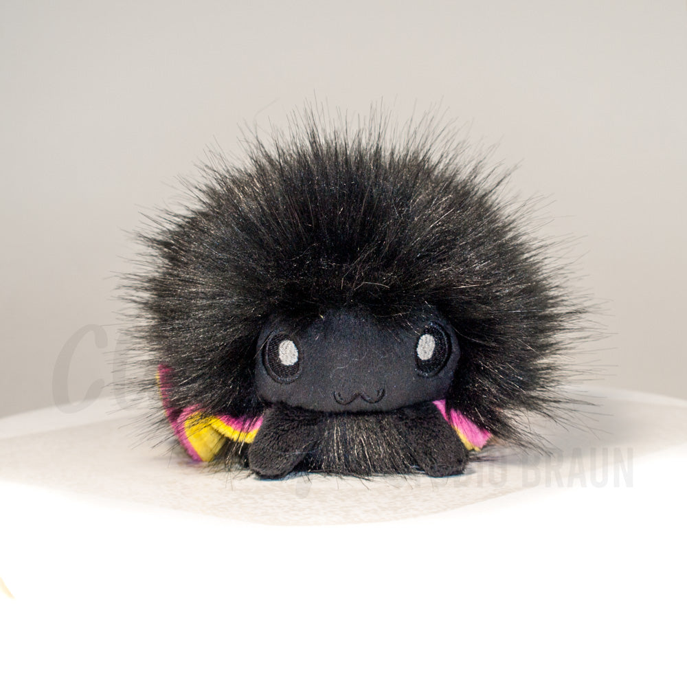 Front view of a cuttlepod plush toy, showcasing its unique form with large, cartoonish eyes, ruffled fins, and a cuddly, furry texture.