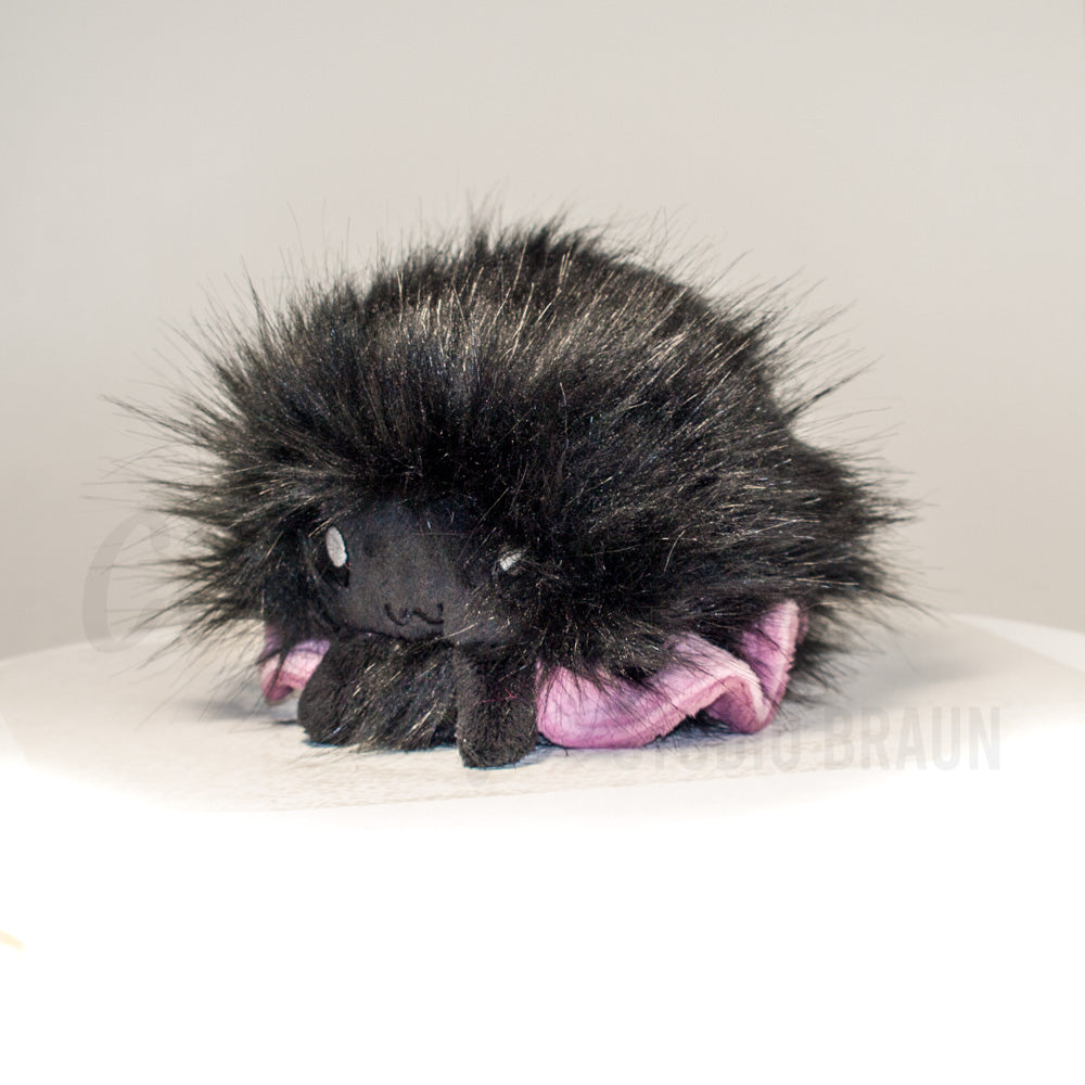 Front view of a cuttlepod plush toy, captured at a slight angle to highlight its charming features: large, cartoonish eyes, ruffled fins, and a cuddly, furry texture.