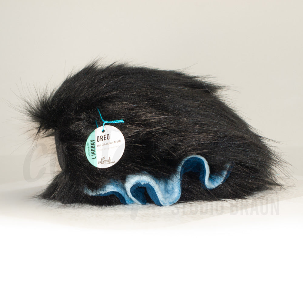 Side profile view of a cuttlepod plush toy, showcasing two-tone ruffled fins, and a cuddly, furry body.