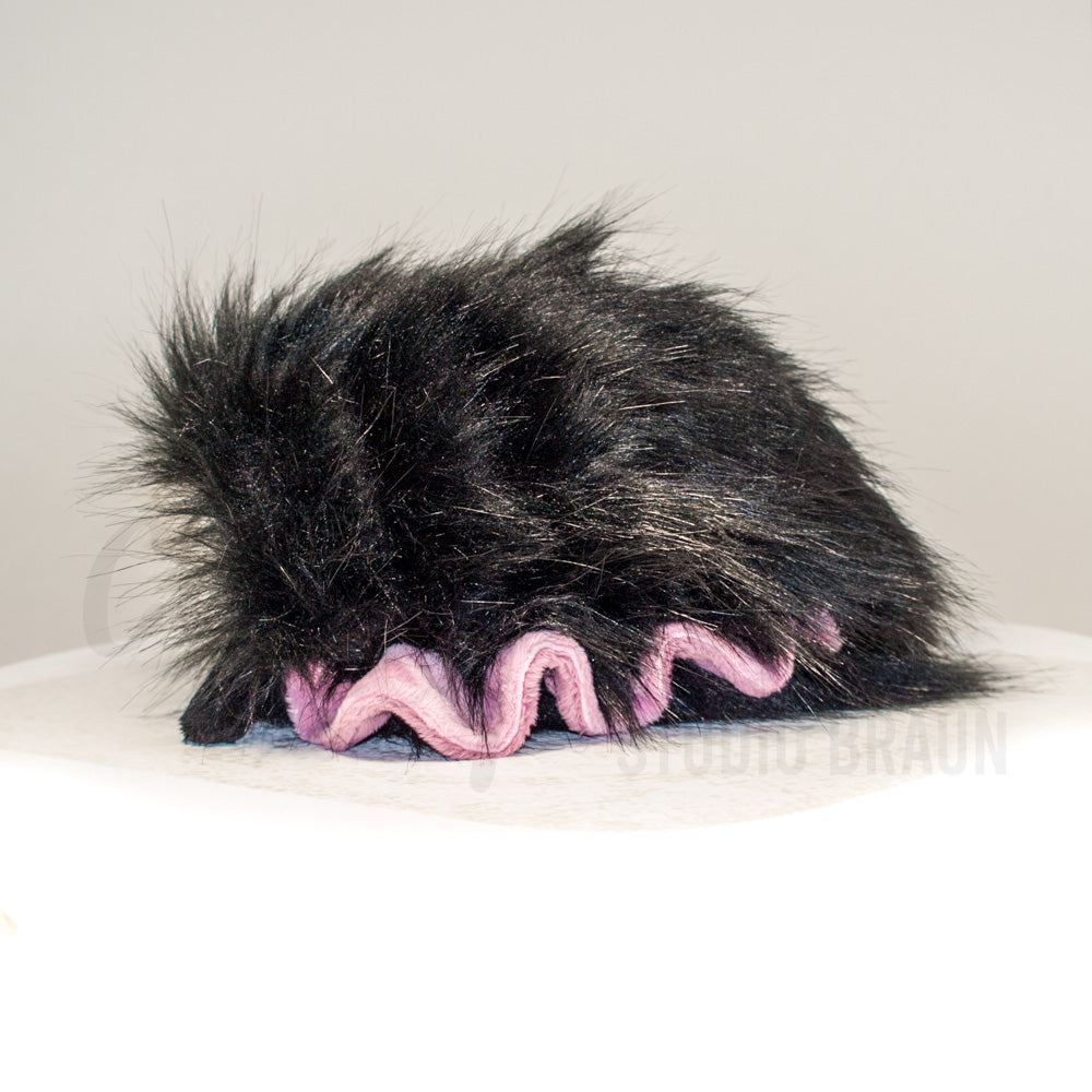 Side profile view of a cuttlepod plush toy, showcasing two-tone ruffled fins, and a cuddly, furry body.