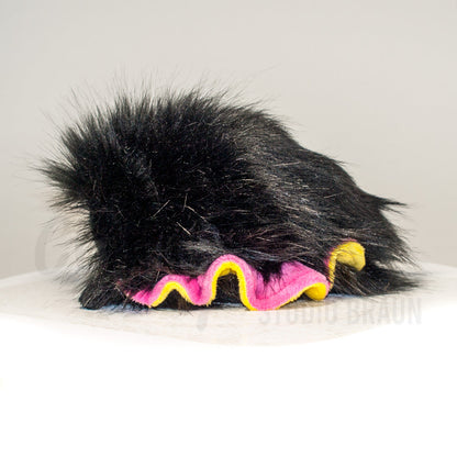 Side profile view of a cuttlepod plush toy, showcasing two-tone ruffled fins, and a cuddly, furry body.