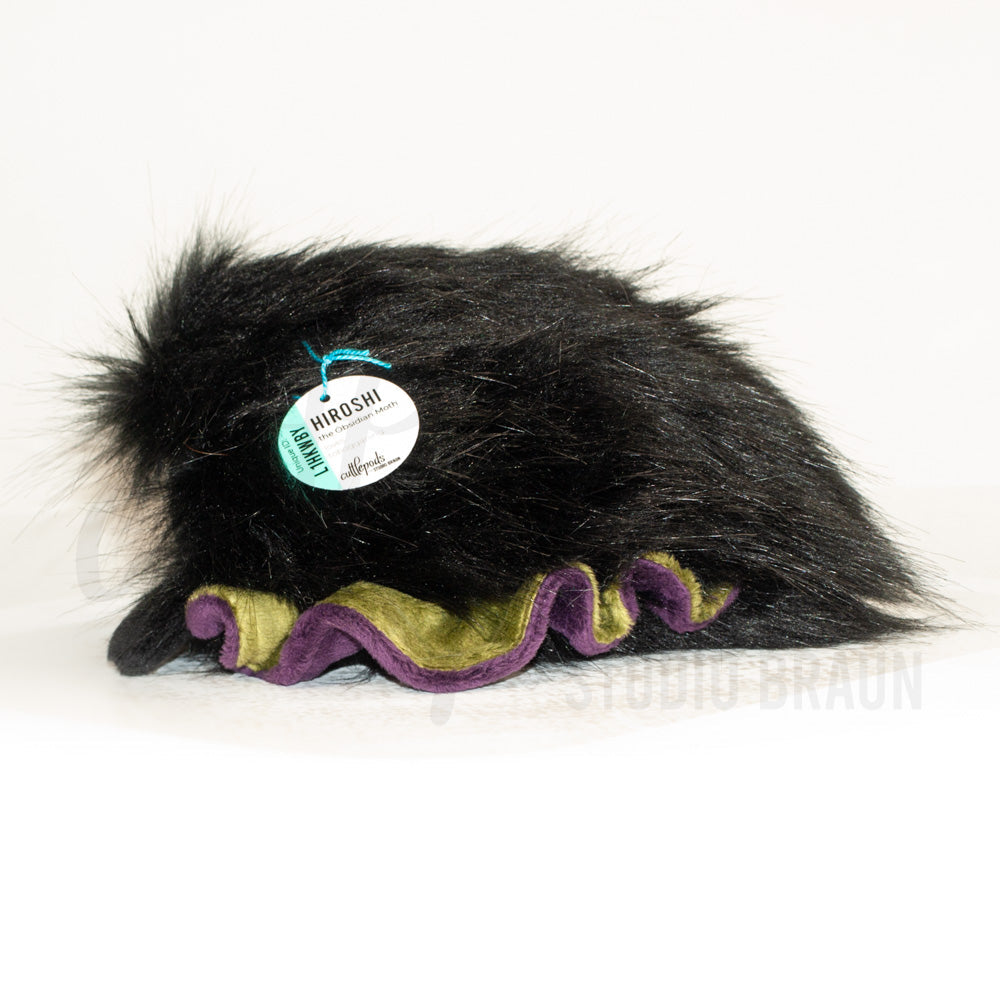 Side profile view of a cuttlepod plush toy, showcasing two-tone ruffled fins, and a cuddly, furry body.