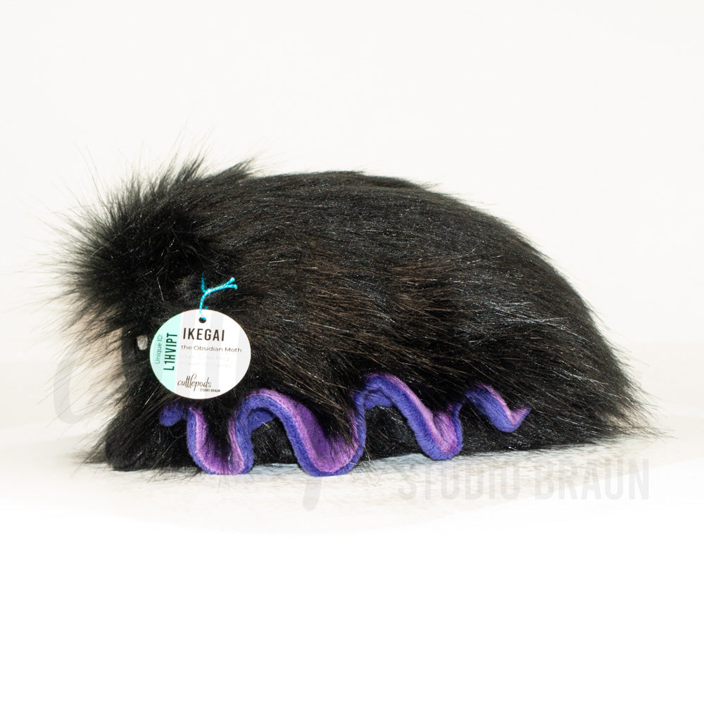 Side profile view of a cuttlepod plush toy, showcasing two-tone ruffled fins, and a cuddly, furry body.