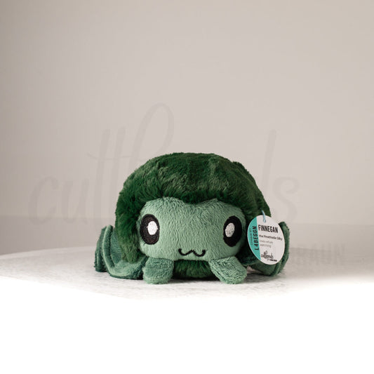 Front view of a cuttlepod plush toy, showcasing its unique form with large, cartoonish eyes, ruffled fins, and a cuddly, furry texture.