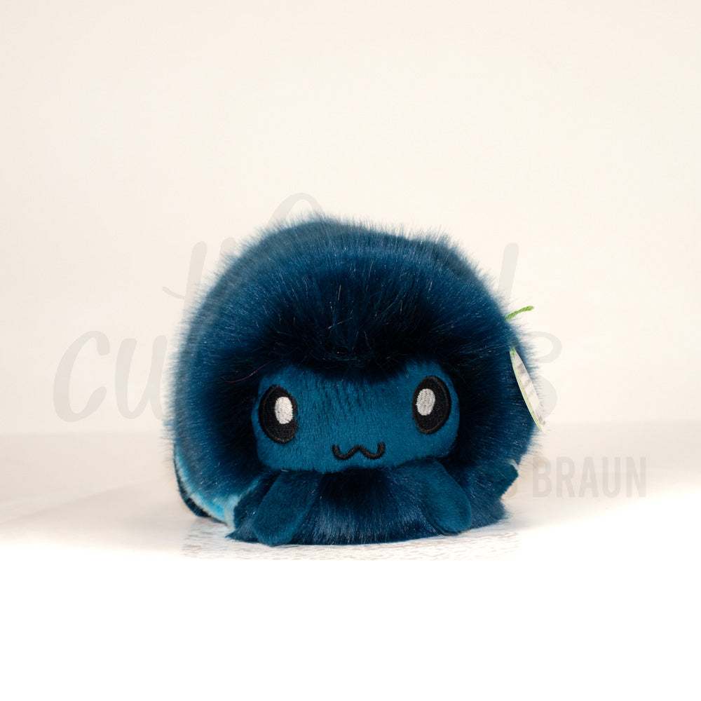 Front view of a cuttlepod plush toy, showcasing its unique form with large, cartoonish eyes, ruffled fins, and a cuddly, furry texture.