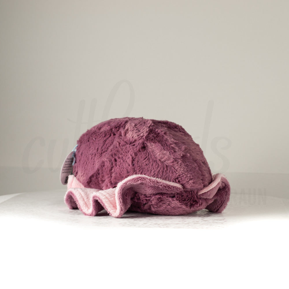 Slightly angled back view of a cuttlepod plush toy, highlighting two-tone ruffled fins, and a cuddly, furry body that comes to a soft point at the rear.