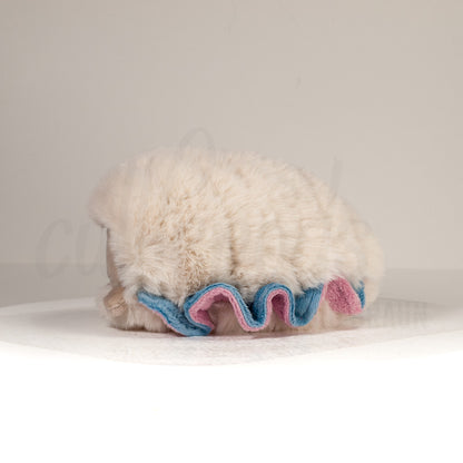 Side profile view of a cuttlepod plush toy, showcasing two-tone ruffled fins, and a cuddly, furry body.