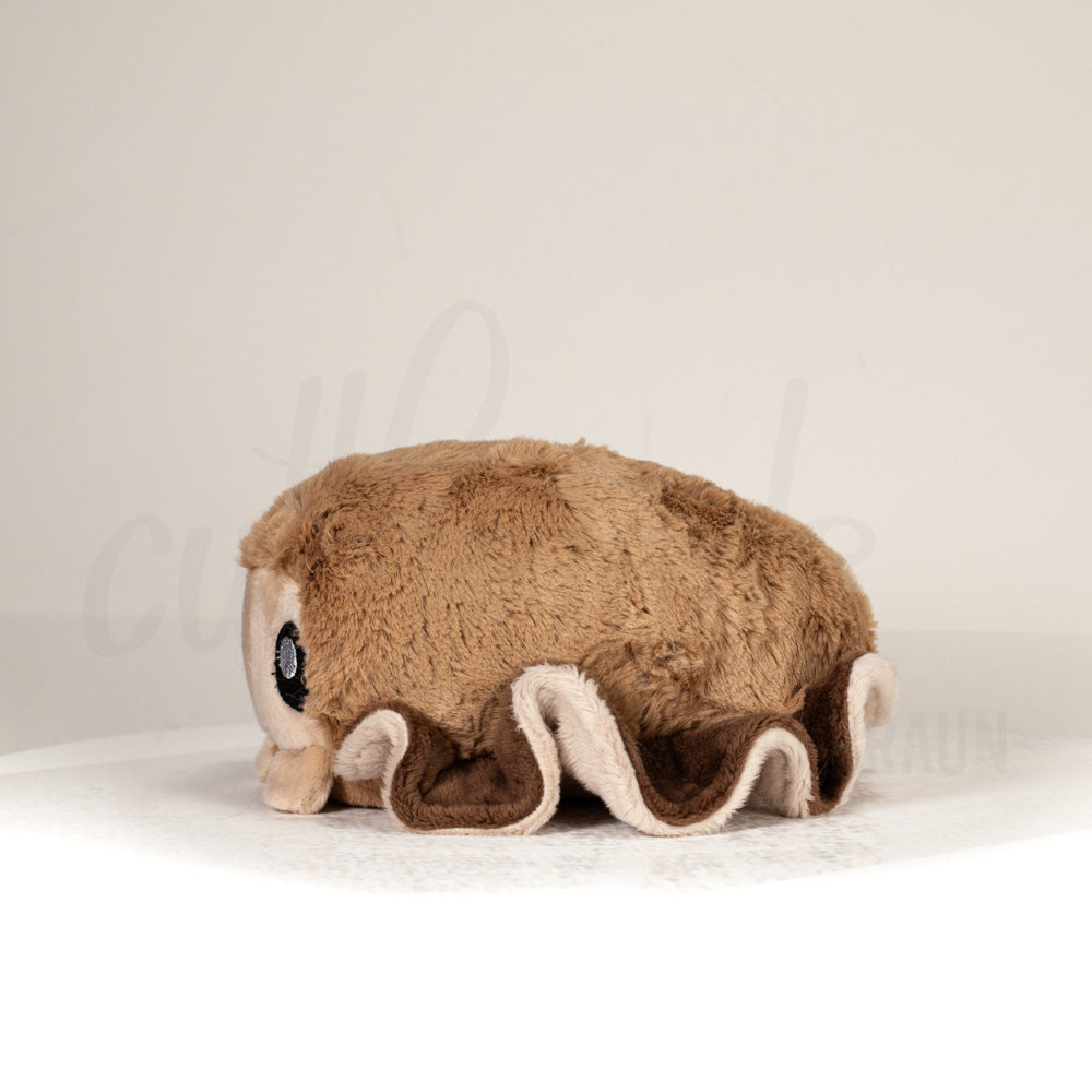 Side profile view of a cuttlepod plush toy, showcasing two-tone ruffled fins, and a cuddly, furry body.