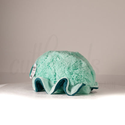 Slightly angled back view of a cuttlepod plush toy, highlighting two-tone ruffled fins, and a cuddly, furry body that comes to a soft point at the rear.