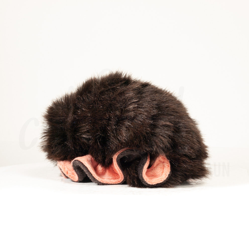 Slightly angled back view of a cuttlepod plush toy, highlighting two-tone ruffled fins, and a cuddly, furry body that comes to a soft point at the rear.