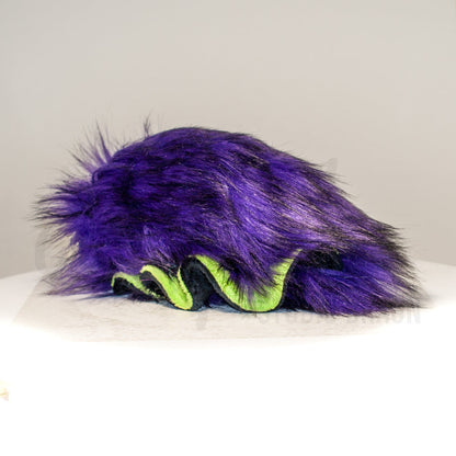 Slightly angled back view of a cuttlepod plush toy, highlighting two-tone ruffled fins, and a cuddly, furry body that comes to a soft point at the rear.