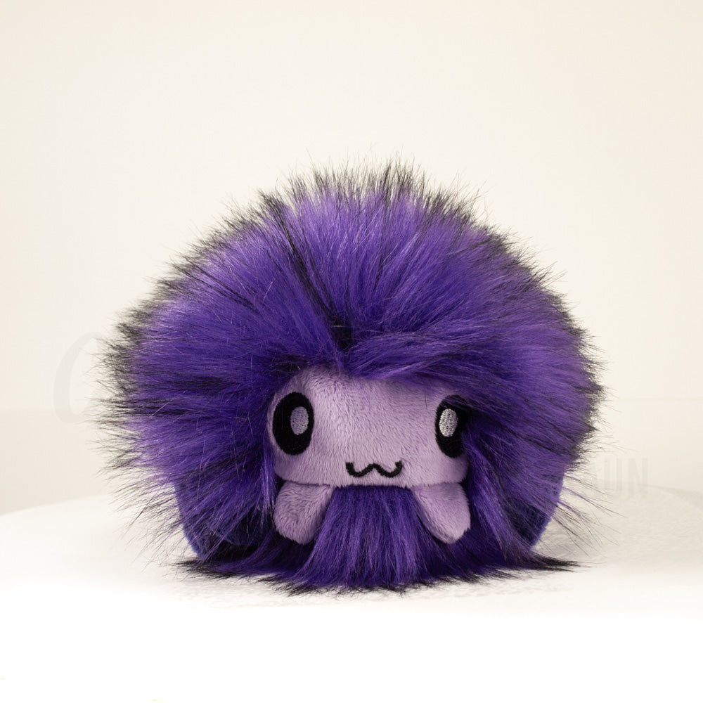 Front view of a cuttlepod plush toy, showcasing its unique form with large, cartoonish eyes, ruffled fins, and a cuddly, furry texture.