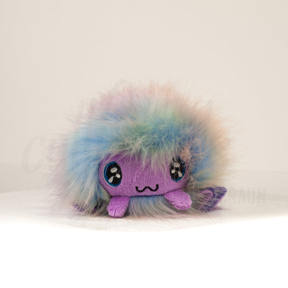 Front view of a cuttlepod plush toy, showcasing its unique form with large, cartoonish eyes, ruffled fins, and a cuddly, furry texture.