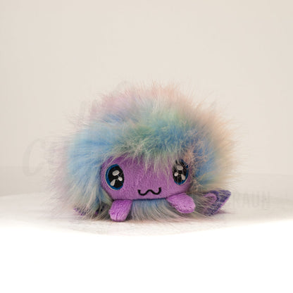 Front view of a cuttlepod plush toy, showcasing its unique form with large, cartoonish eyes, ruffled fins, and a cuddly, furry texture.