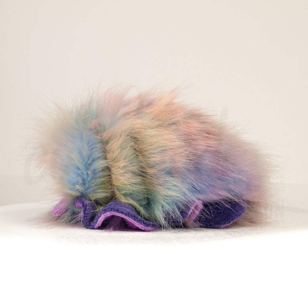 Side profile view of a cuttlepod plush toy, showcasing two-tone ruffled fins, and a cuddly, furry body.