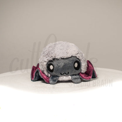 Front view of a cuttlepod plush toy, showcasing its unique form with large, cartoonish eyes, ruffled fins, and a cuddly, furry texture.